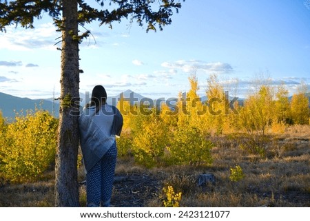Women Stands Peacefully Looking at Mountain Peak Through Trees a