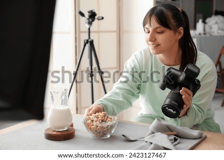 Female food photographer preparing for shooting tasty cereal rings with milk in studio