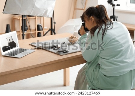 Female food photographer taking picture of tasty cereal rings with milk in studio