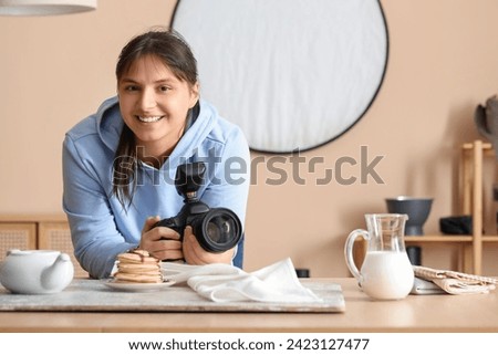 Female food photographer with camera shooting tasty pancakes in studio