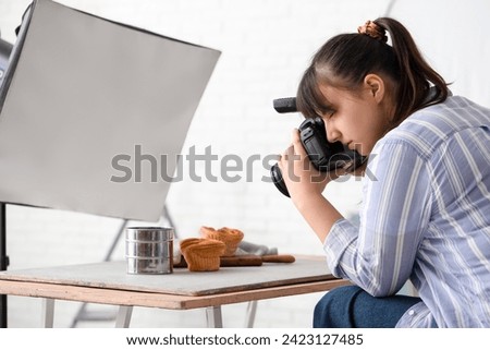 Female food photographer taking picture of tasty cakes in studio
