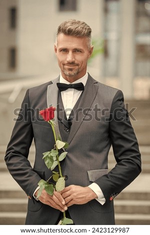 special occasion formalwear. cheerful man with rose for special occasion. tuxedo man outdoor Royalty-Free Stock Photo #2423129987