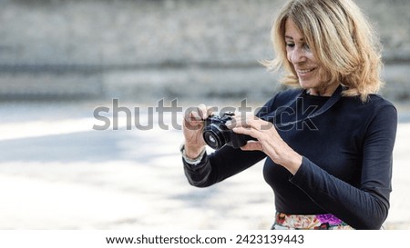 caucasian 70s senior fit happy lady relax with photo camera in park wear floral skirt and black long sleeve shirt