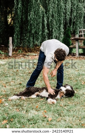 Mid adult man playing with tired, panting dog outdoors