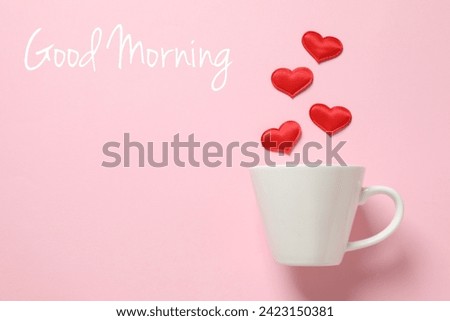White cup with red hearts and text GOOD MORNING on color background
