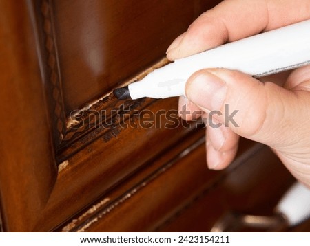 Furniture marker, restoration of wooden furniture. the master fixes a scratch on the facade Royalty-Free Stock Photo #2423154211