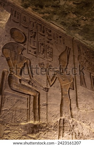 Ancient Hieroglyphs, including the god Horus, on a wall of Abu Simbel Royalty-Free Stock Photo #2423161207