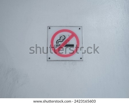 no smoking sign on a white wall at the subway station