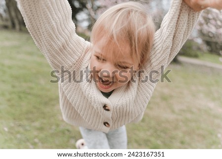 Cute blonde girl having fun in the park near a blooming magnolia