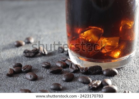 Close-up picture of iced coffee with Coffee beans in a gray background.