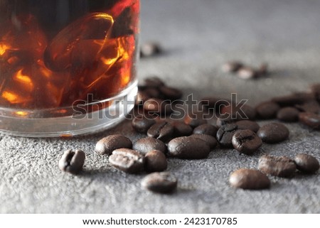 Close-up picture of iced coffee with Coffee beans in a gray background.