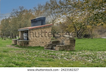 Youths cooking food on an outdoor BBQ in a stone built hut at a park beside the Ebro river