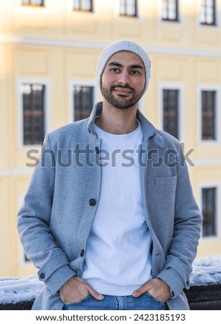 Portrait of a handsome young man. Smiling Asian man with a neat beard wearing a light coat and a white knitted hat