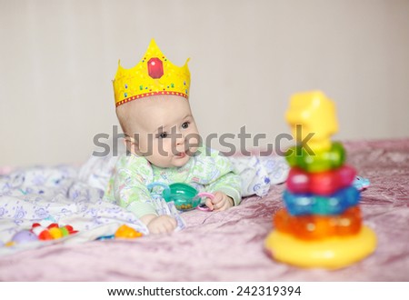 child in the crown lies on a bed with toys