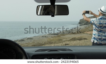 Lone traveler on vacation with rental car photographs the ocean during the break. Travel concepts