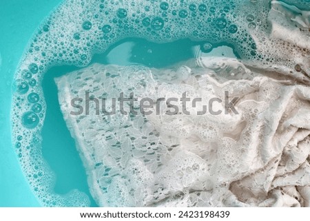 Women's lace dress soaked in water dissolved detergent with white foam bubble. Laundry concept