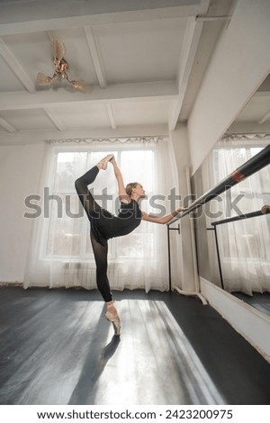 Beautiful asian ballerina doing bilman exercise at barre in dance class. 
