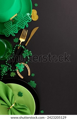 Immersed in Irish spirit: Crafting your St. Paddy's table tale. Top view vertical shot of plates, cutlery, green hat, green beer, party eyewear, festive decor on black background with greeting zone