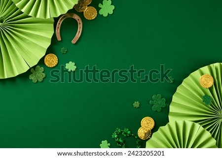 Emerald Extravaganza: marking St. Patrick's Day with panache. Top view photo of folding fans, horseshoe, trefoils, coins, beads on green background with space for greeting text