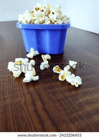 A bowl full of popcorn on the wooden table.