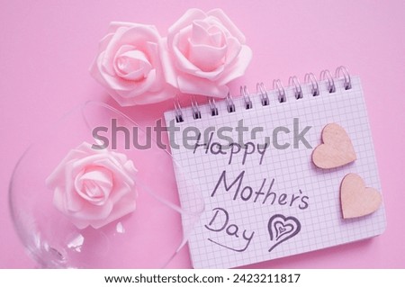 happy mothers day write in notepad next to roses 