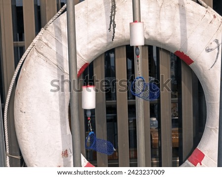 Still life with old white lifebuoy and fishing rods with bait cages and lead sinkers, Oshima island, Japan Royalty-Free Stock Photo #2423237009