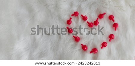 Red love symbol from kids toys for valentine on white fur background. Space for text.