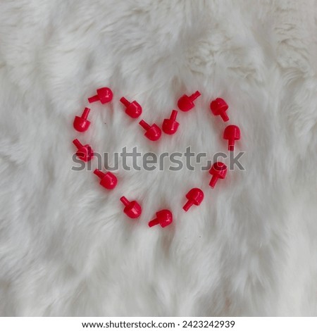 Red love symbol from kids toys for valentine on white fur background