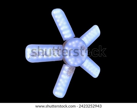 black background picture Pictured is a white multi-purpose light bulb with five wings in one. It can be used outdoors. Easy to attach to a tent or canvas roof. There are dead insects in the bulb. 