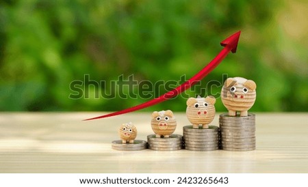 Money coins stack topping with wooden piggy bank and red arrow up on wooden table with natural background, Saving money concept for preparing in future, Growth money stability, Financial investment. Royalty-Free Stock Photo #2423265643
