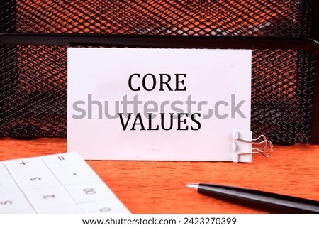 CORE VALUES word written on a white card next to the calculator, a pen on an orange background Royalty-Free Stock Photo #2423270399