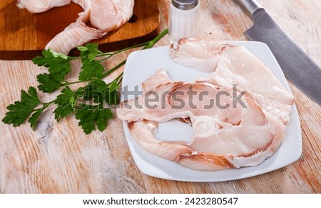 Raw juicy steaks of blue shark with fresh greens on wooden background. Cooking ingredients
