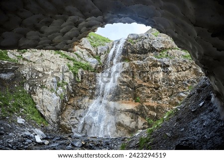 A large beautiful waterfall flowing down from a cliff into an ice cave. Natural landscape