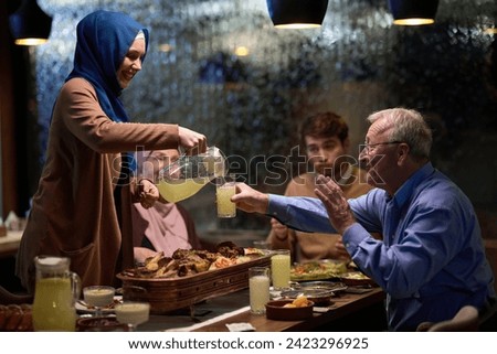 A modern and traditional European Islamic family comes together for iftar in a contemporary restaurant during the Ramadan fasting period, embodying cultural harmony and familial unity amidst a Royalty-Free Stock Photo #2423296925