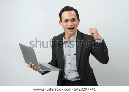 Happy asian indonesian business man in suit holding laptop computer on isolated background