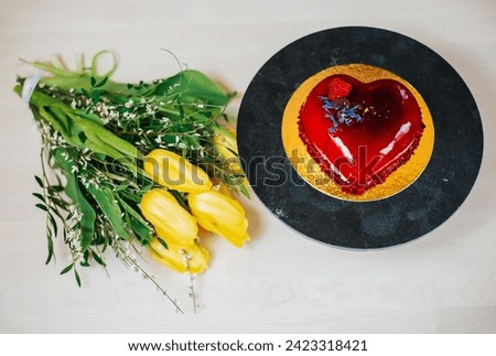 Valentine's Day yellow tulips and red cake in the shape of a heart