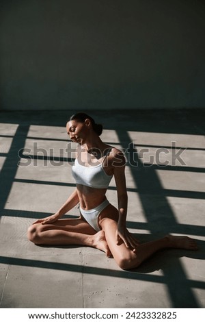 Fitness woman in white clothes is indoors in sunlight.