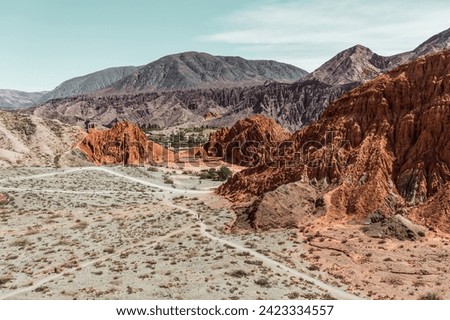 Striking landscape, colorful reddish formations of Pumamarca, Jujuy, Argentina. A whitish trail crosses the landscape.