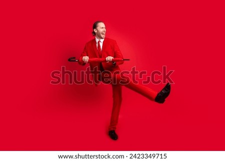 Full body photo of attractive young man dancing energetic umbrella showman dressed stylish classic clothes isolated on red color background