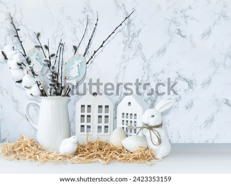 Easter composition on a light background.  Cute white rabbits, willow twigs, Easter eggs symbol of the Easter holiday.  Home and office decoration.  The bright holiday of Easter.