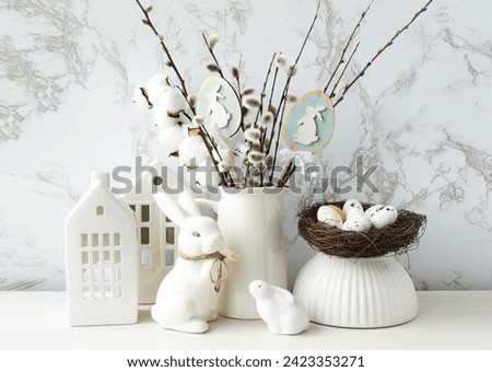 Easter composition on a light background.  Cute white rabbits, willow twigs, Easter eggs symbol of the Easter holiday.  Home and office decoration.  The bright holiday of Easter.