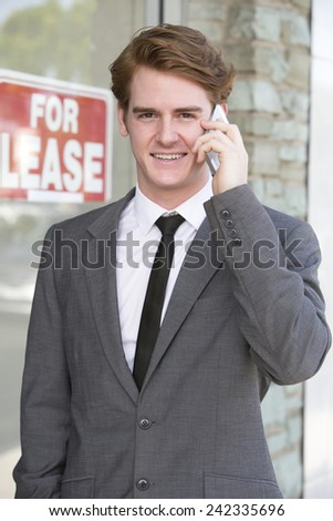 man in front of a store with a "for lease" sign on the phone