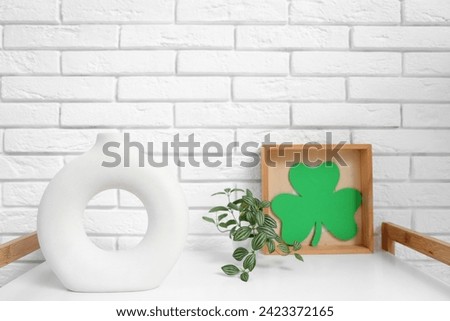 Clover, houseplant and decorative vase on table in living room, closeup. St. Patrick's Day celebration