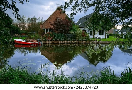 Lakehouse at rural pond. A house with a boat on the pond. Village house at pond. Pond in village