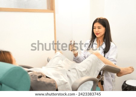 scene of a woman gynecologist is wearing medical gloves and doing internal examination of a female patient or pregnant woman that lying on a gynecological chair in the medical treatment room Royalty-Free Stock Photo #2423383745