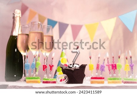 Birthday with champagne and glasses. Birthday candle with number 7. Anniversary card with garlands save space. Festive background.