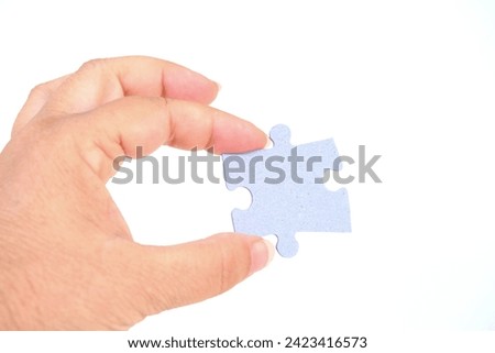 female hand holds cardboard puzzle piece, logical skills, puzzle solving and memory improvement, business concept for completing