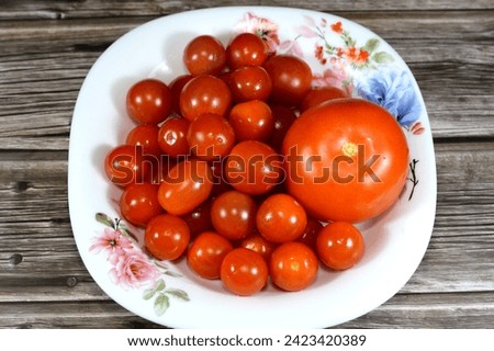 Tomato and cherry tomatoes, cherry tomato is a type of small round tomato believed to be an intermediate genetic admixture between wild currant-type tomatoes and domesticated garden tomatoes Royalty-Free Stock Photo #2423420389