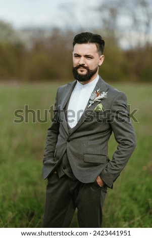 portrait of a young bearded guy groom on a green meadow