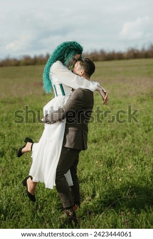a bearded groom and a girl with green hair dance and twirl in a spring meadow